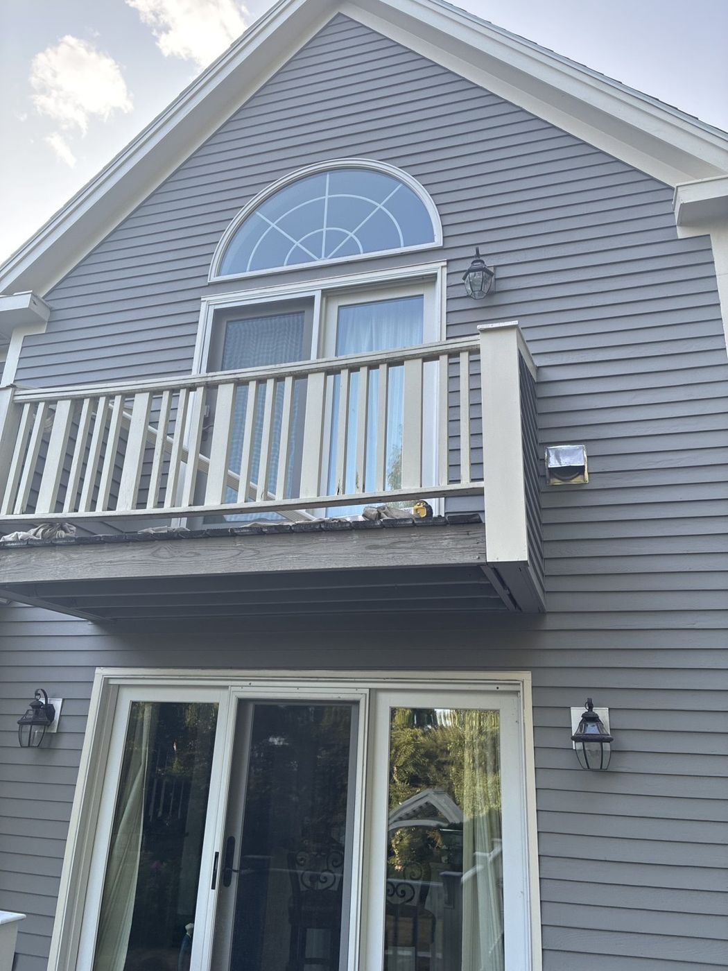 Gray house with arched window and white balcony after painting