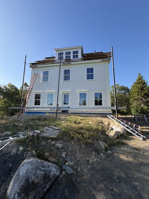 White clapboard house painted from scaffolding